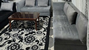 Una sala de estar con un sofá gris, una mesa de centro de madera y un tapete estampado.