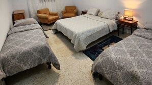 Un dormitorio con dos camas, una silla, una mesita de noche y una lámpara.
