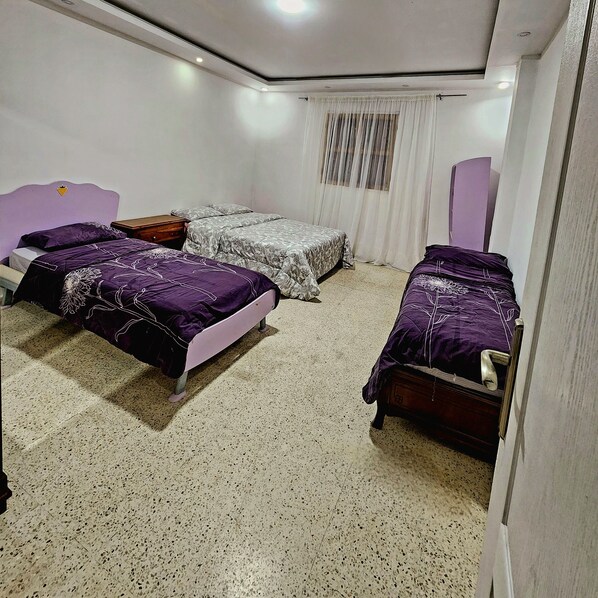 A bedroom with two single beds, a small wooden dresser, and a large mirror.