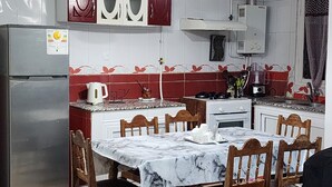 Una cocina con una mesa de mármol, sillas de madera, un refrigerador y un microondas.