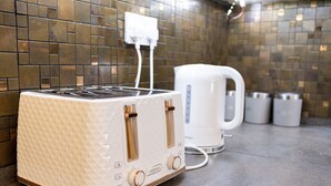 Une cuisine avec un grille-pain blanc et une bouilloire blanche posés sur un plan de travail.