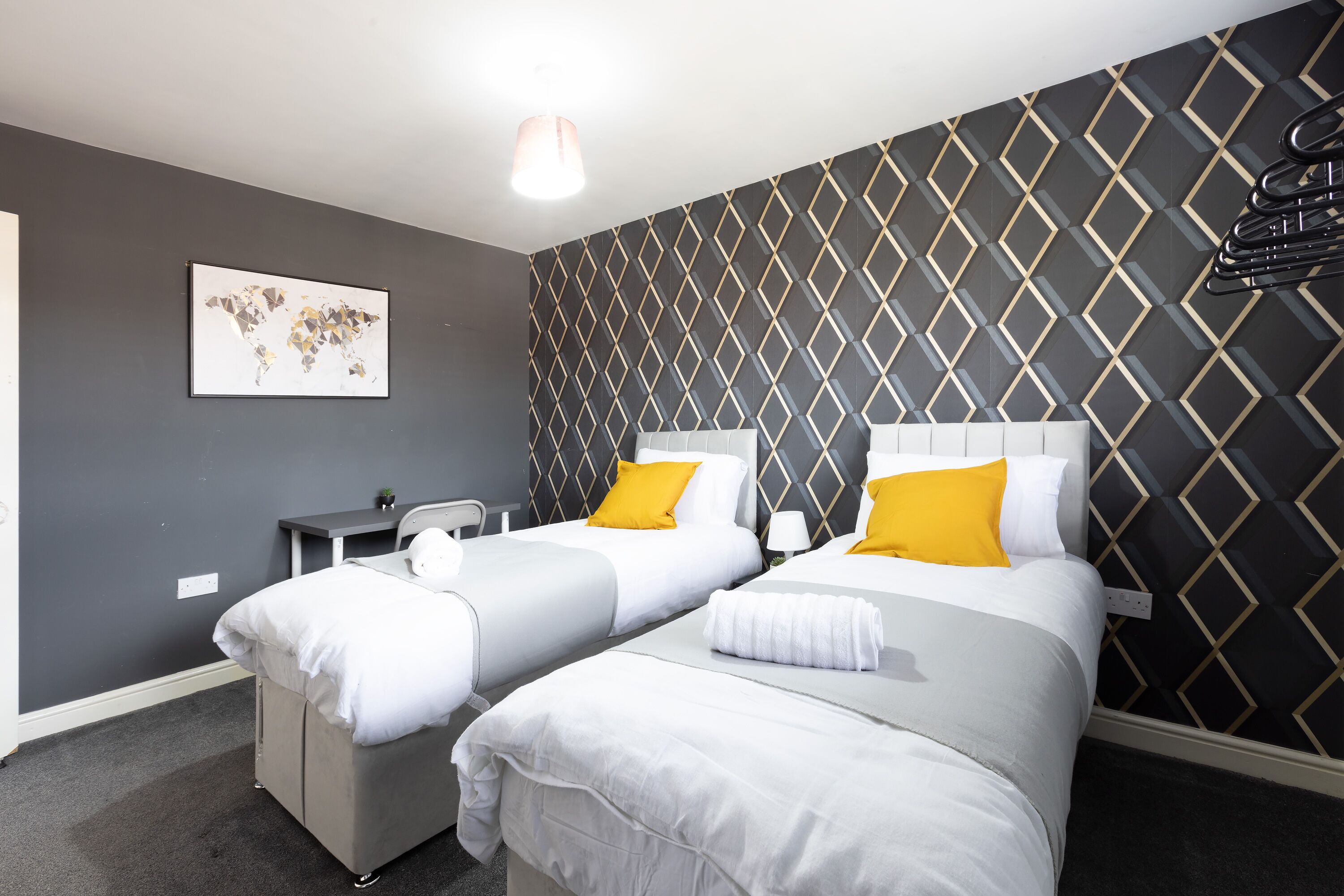 Habitación de hotel con dos camas, un escritorio, una silla y un mapa mundial en la pared.