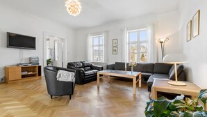 Ein modernes Wohnzimmer mit Flachbildfernseher, Ledersofas, einem Holztisch und einer Stehlampe.