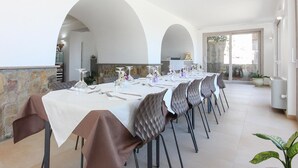 A dining area with a long table set for a meal, flanked by stone walls and arched doorways. - Amazing home in Laureana Cilento (Laureana Cilento)