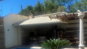 A swimming pool with a tiled edge, a pergola, and a palm plant. - Quarto Aconchegante (Vila Velha)