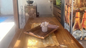 A bar area with a wooden counter, a refrigerator with beer bottles, and a brick wall. - Quarto Aconchegante (Vila Velha)