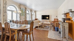 A spacious living area with a dining table, chairs, a sofa, a television, and a fireplace.