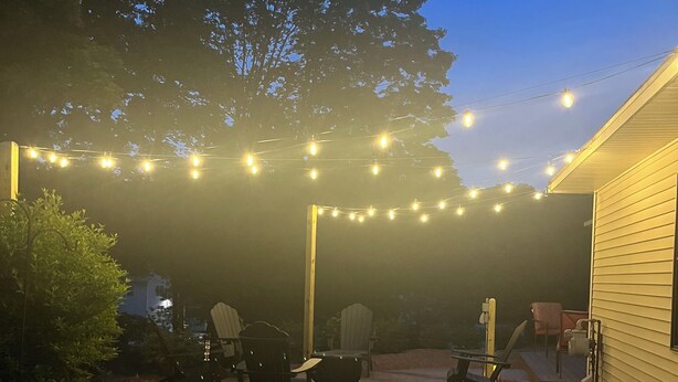 An outdoor patio area with string lights, a concrete pathway, and outdoor furniture.