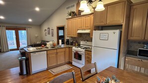 A modern kitchen with wooden cabinets, a central island, and a dining area with a wooden table and chairs.