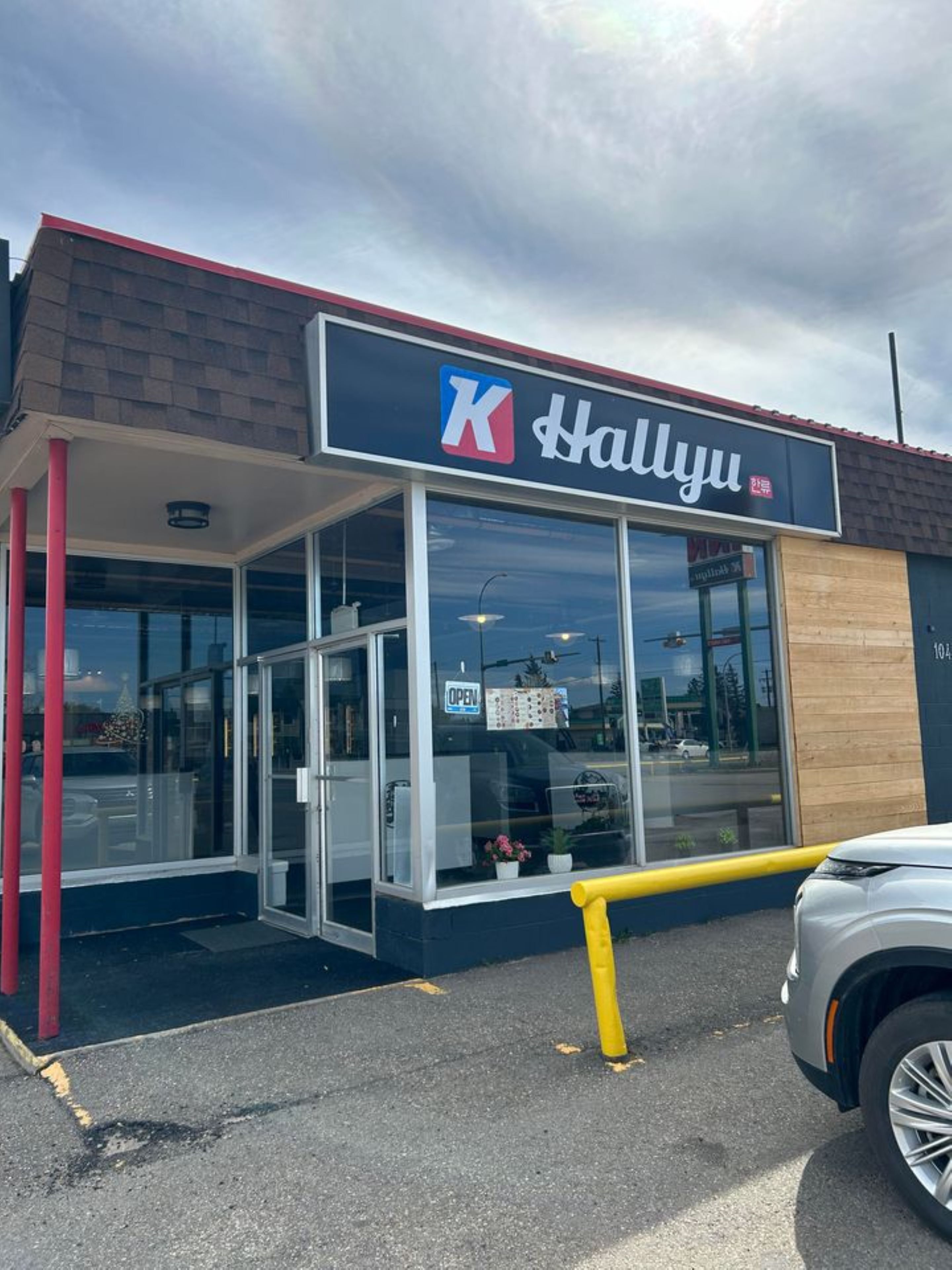 A K Hallyu store with a clear entrance, large windows, and a visible 'OPEN' sign. - PARKSIDE INN (Grande Prairie)