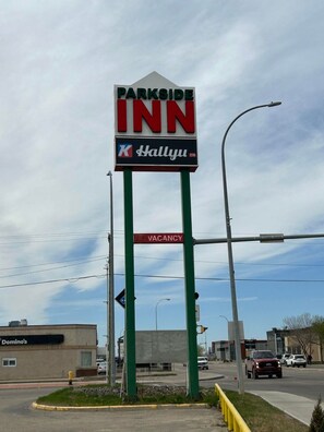 Letrero de PARKSIDE INN con un logotipo de K HALLYU y un letrero que dice 'NO HAY HABITACIONES DISPONIBLES'.