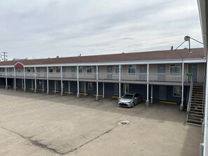 Un motel con una zona de estacionamiento central y un pasillo cubierto.