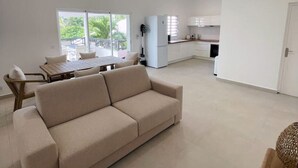 A spacious living area with a sofa, a dining table, and a kitchen in the background.