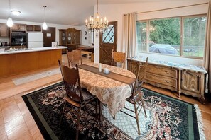 Un espace repas comprenant une table, des chaises, un lustre et une vue par une fenêtre.