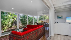 A spacious living area with a large window, a red sofa, and a dining table. - Gorgeous Grove Contemporary Family Home (Sarasota)