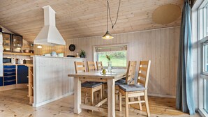 Un intérieur en bois comprenant un coin repas, une cuisine et de grandes fenêtres.