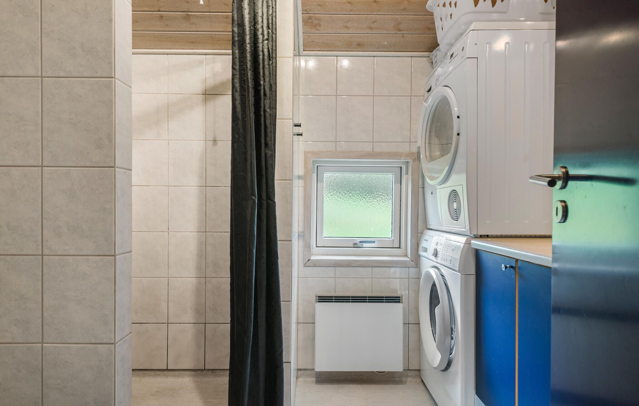 A laundry room with a washing machine, dryer, and a small window.