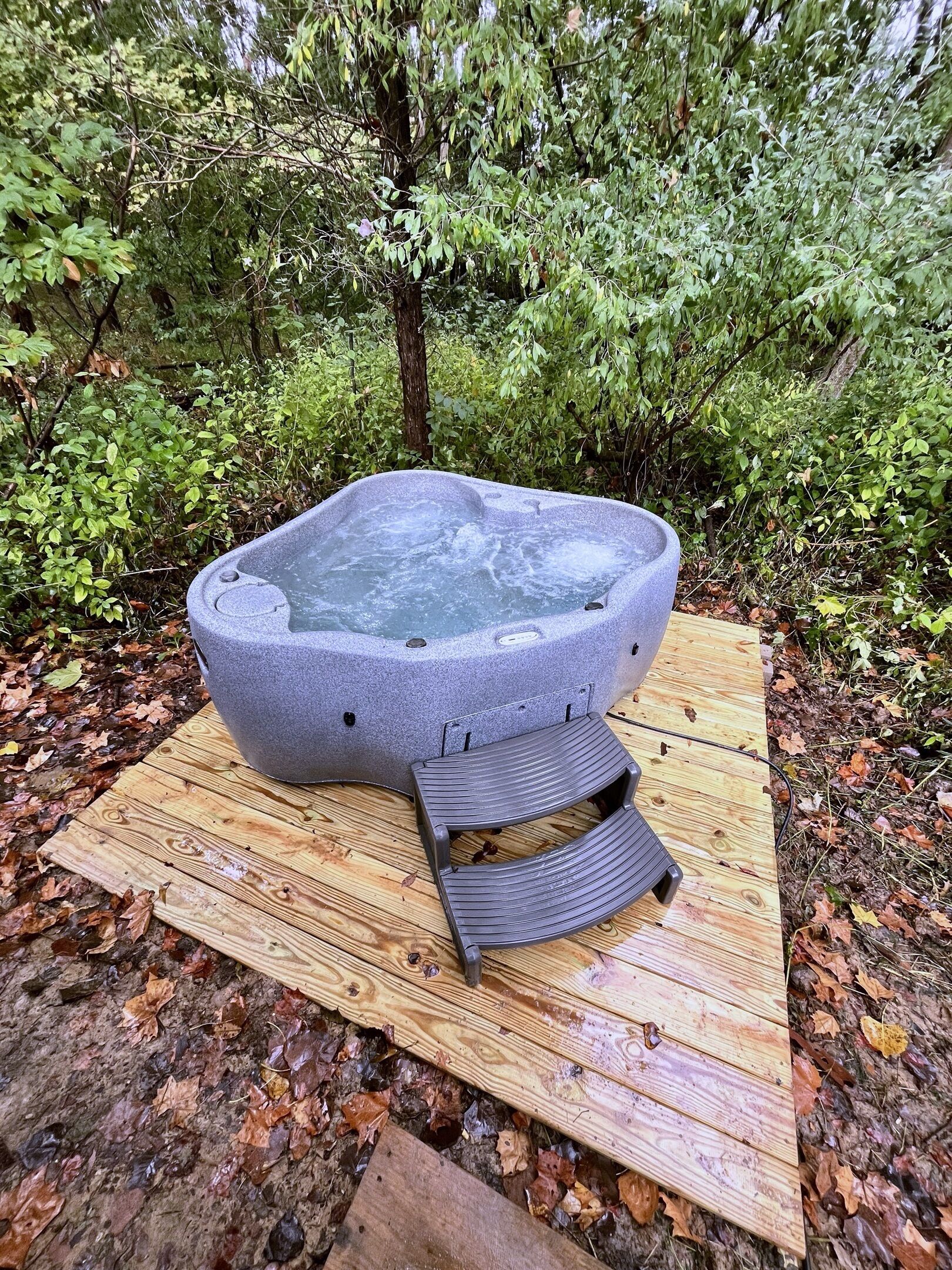 Ett bubbelbad i ett skogsområde med ett trädäck.
