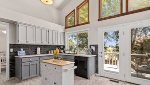 A modern kitchen with grey cabinets, a black backsplash, and a wooden countertop. There is a built-in dishwasher and a fruit bowl on the counter. - Stylish 4 level home in a quiet safe neighborhood nestled in a cul-de-sac.  (Pueblo)