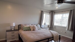 A bedroom with a bed, two bedside tables, a ceiling fan, and windows with curtains. - Stylish 4 level home in a quiet safe neighborhood nestled in a cul-de-sac.  (Pueblo)
