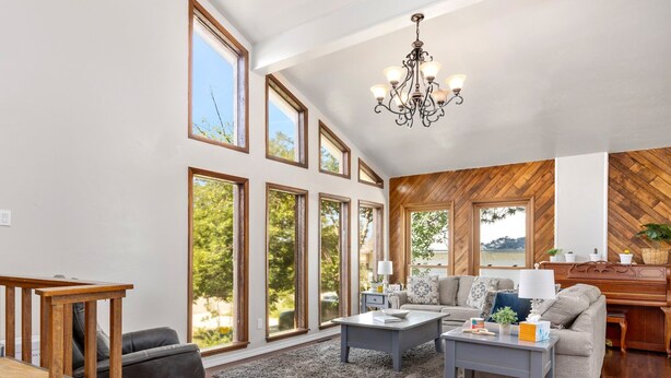 A spacious living room with large windows, a chandelier, and a herringbone-patterned wall. - Stylish 4 level home in a quiet safe neighborhood nestled in a cul-de-sac.  (Pueblo)