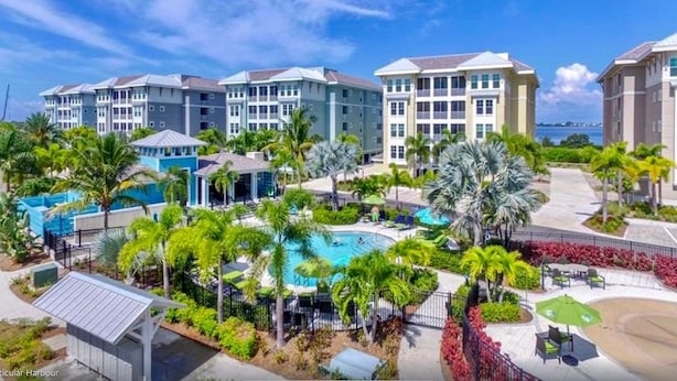 Un resort con varias edificaciones, piscina y palmeras.