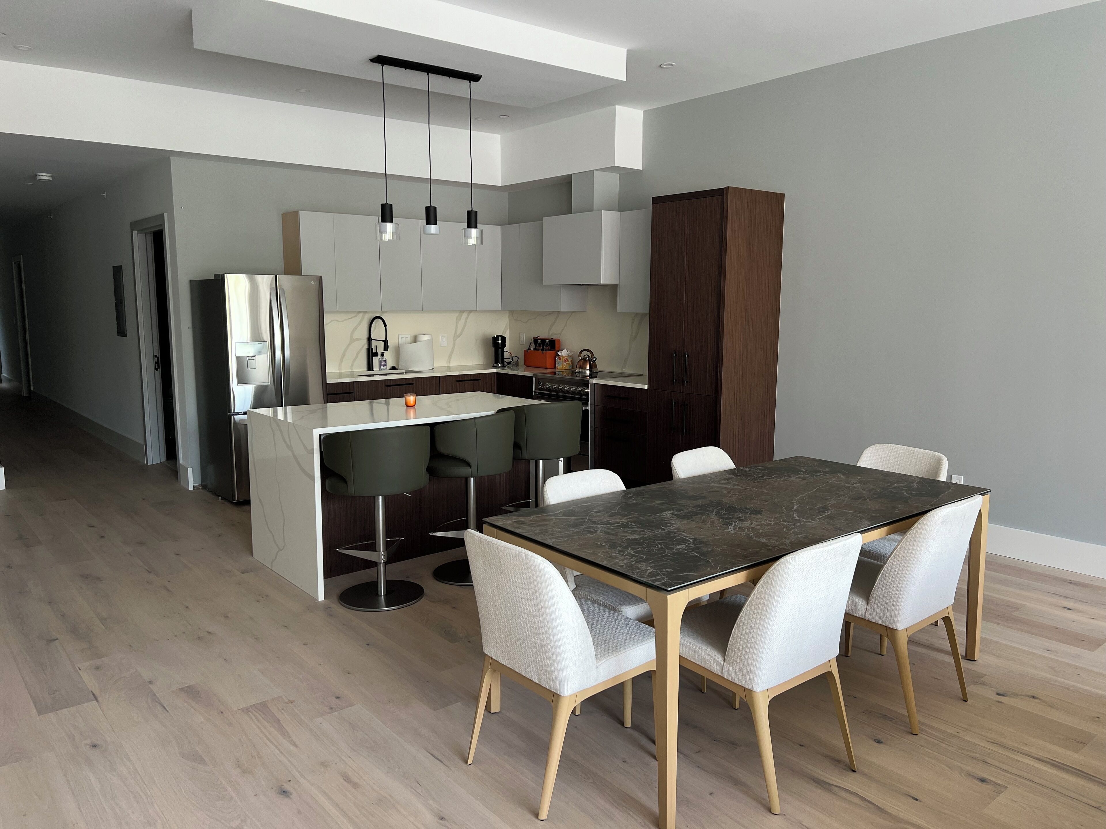 Una cocina moderna con una isla central, taburetes de bar y una mesa de comedor con sillas.