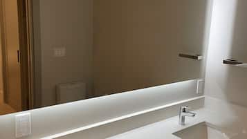 Un baño moderno con dos lavamanos, un espejo grande y un tocador iluminado.