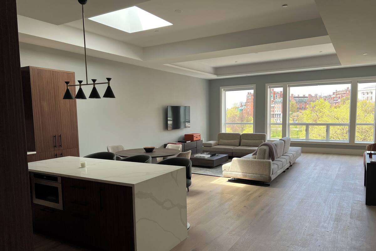 A spacious living area with a large window, a sofa, a coffee table, and a TV.