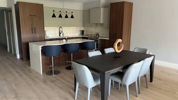 Et moderne køkken med en central ø, barstole og et spisebord med stole.
