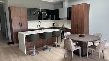 A modern kitchen with a central island, bar stools, and a dining table with chairs.