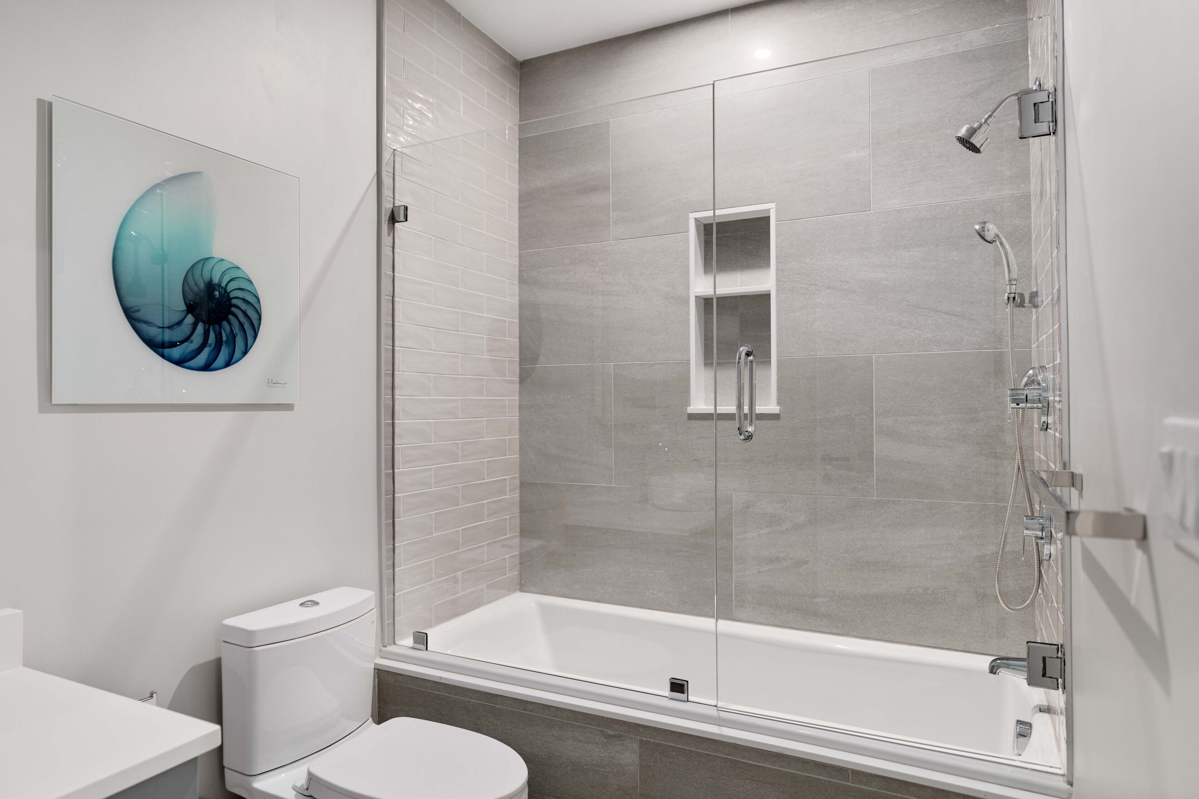 Et moderne badeværelse med bruseniche, toilet og håndvask.