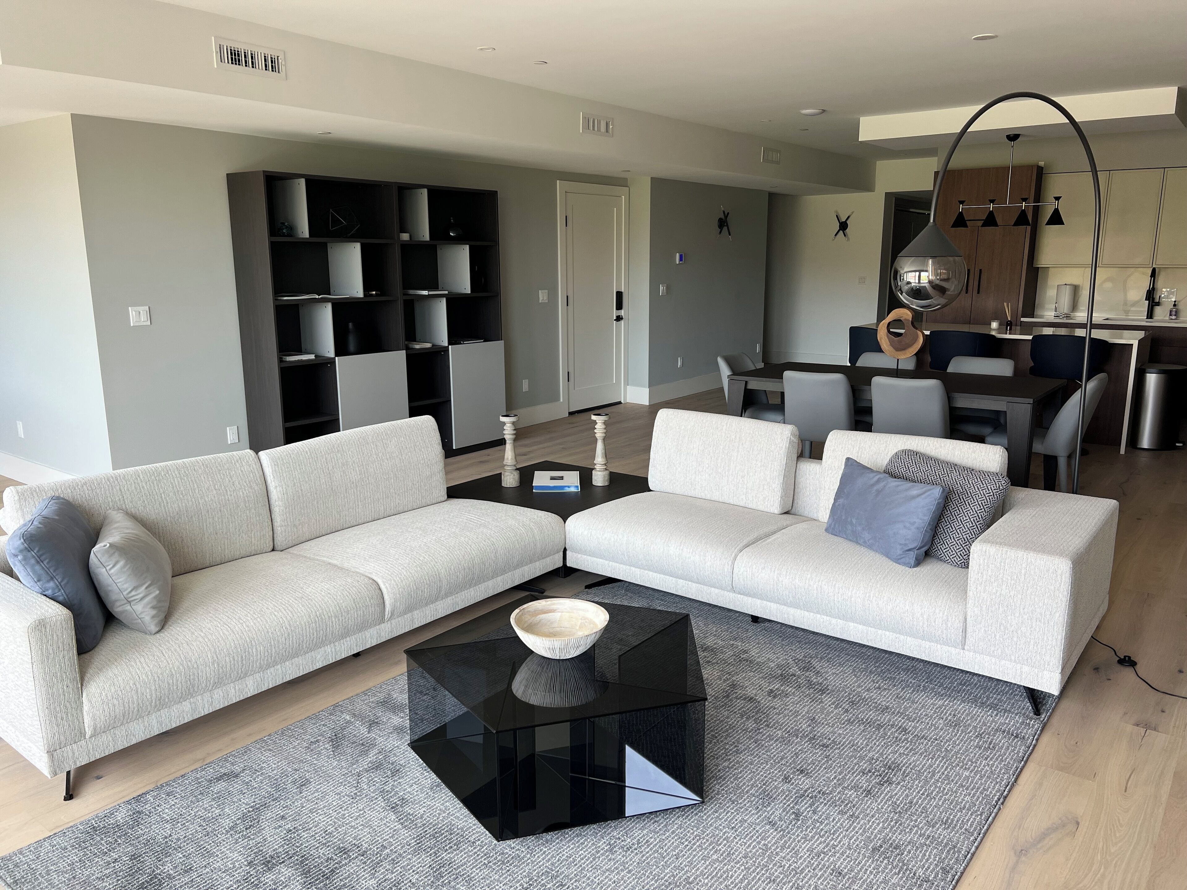 Una sala moderna con un sofá modular, una mesa de centro de vidrio y un comedor con mesa y sillas.