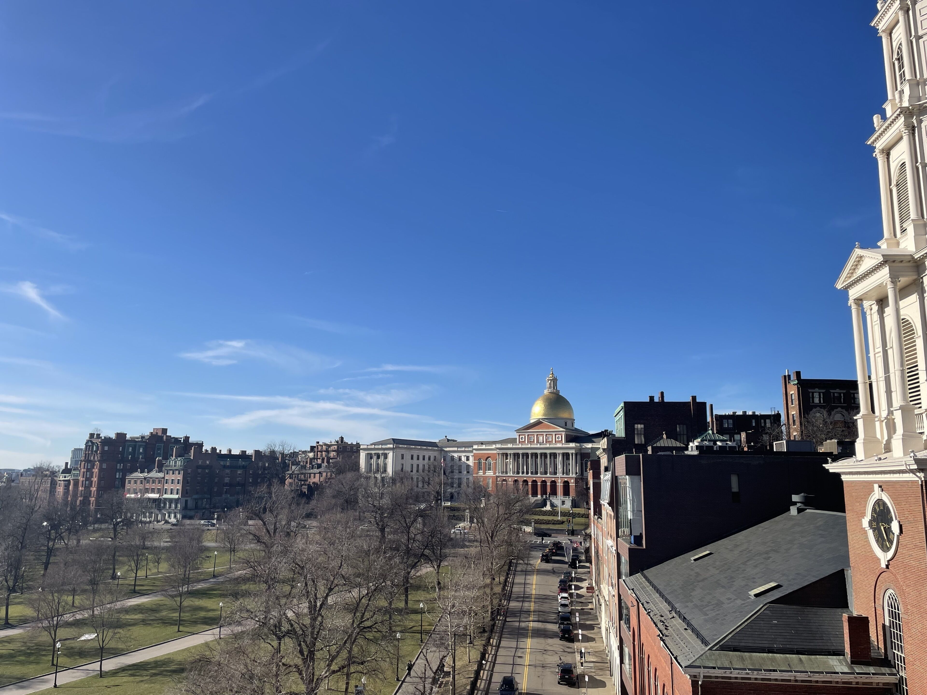 A cityscape with a prominent building featuring a golden dome, surrounded by other structures and a clear sky.
