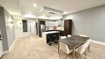 Una cocina moderna con una isla central, armarios blancos y un comedor con una mesa y sillas de mármol.