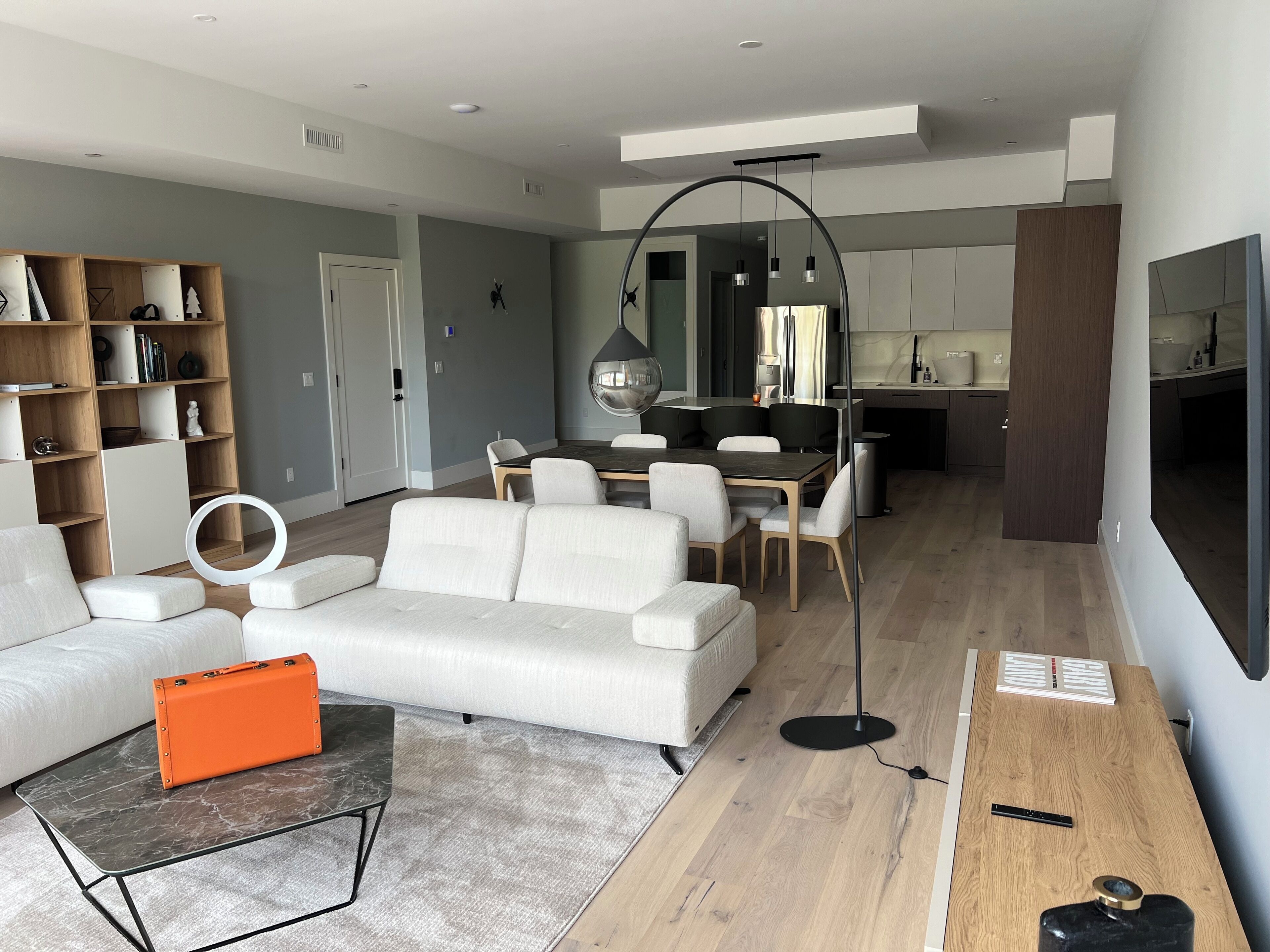 A modern living room with a sofa, coffee table, and a dining area with chairs and a table.