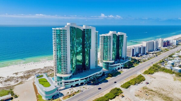 Un hotel de gran altura con fachada curva, una estructura de estacionamiento y vistas a la playa.