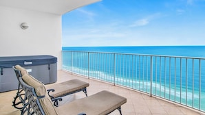 Un balcon avec deux fauteuils confortables et un barbecue, donnant sur une mer d’un bleu limpide.