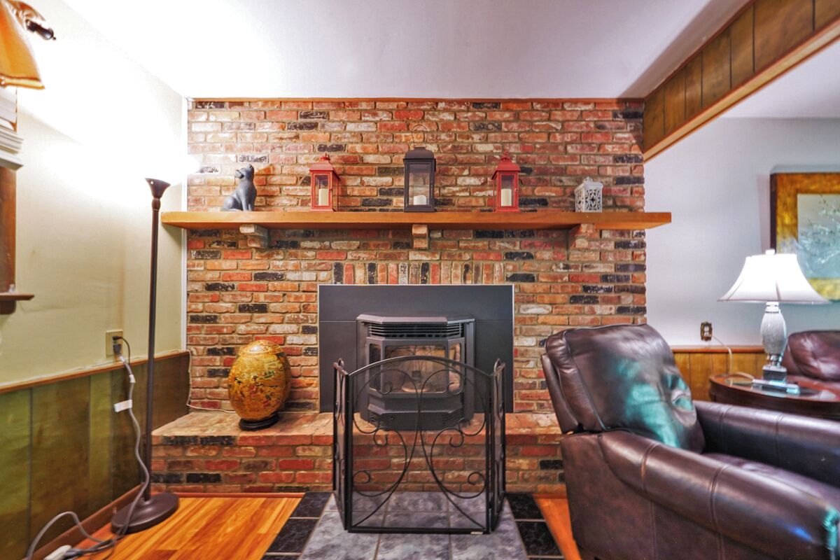 A cozy living room with a brick fireplace, leather sofa, and a globe on a stand.