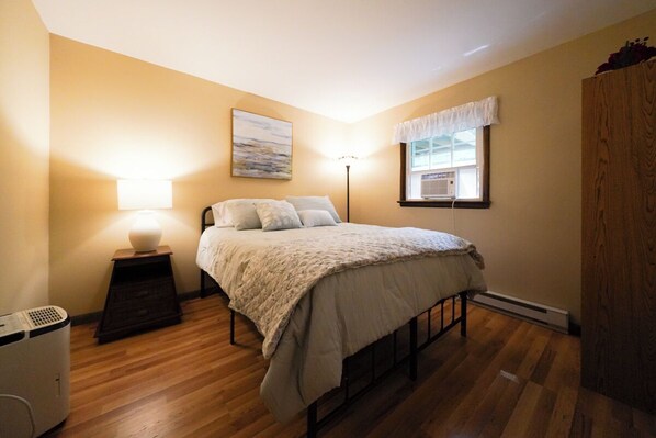A bedroom with a bed, bedside lamp, and a window with a view.