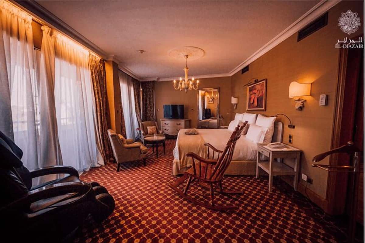 Habitació d'hotel amb un llit, una escriptori, una cadira, una televisió i un penjallum.