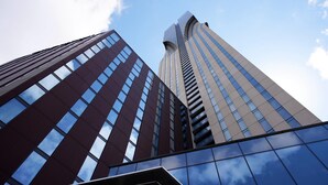 Un edificio alto con un diseño arquitectónico moderno, que presenta una estructura curva destacada en la parte superior.