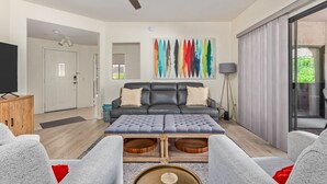 Un salon moderne avec un canapé gris, une table basse en bois et un ventilateur de plafond.