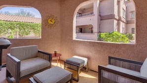 Une pièce avec vue sur un immeuble, un mur décoré d’une œuvre d’art représentant des cactus, et une petite table avec une chaise.