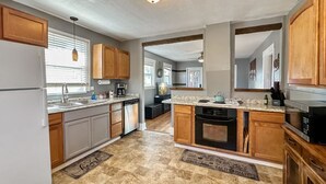 A kitchen with wooden cabinets, a granite countertop, a refrigerator, a stove, and a microwave. - Charming Cascade Cabin: Large Yard, Near Downtown! (Cascade)
