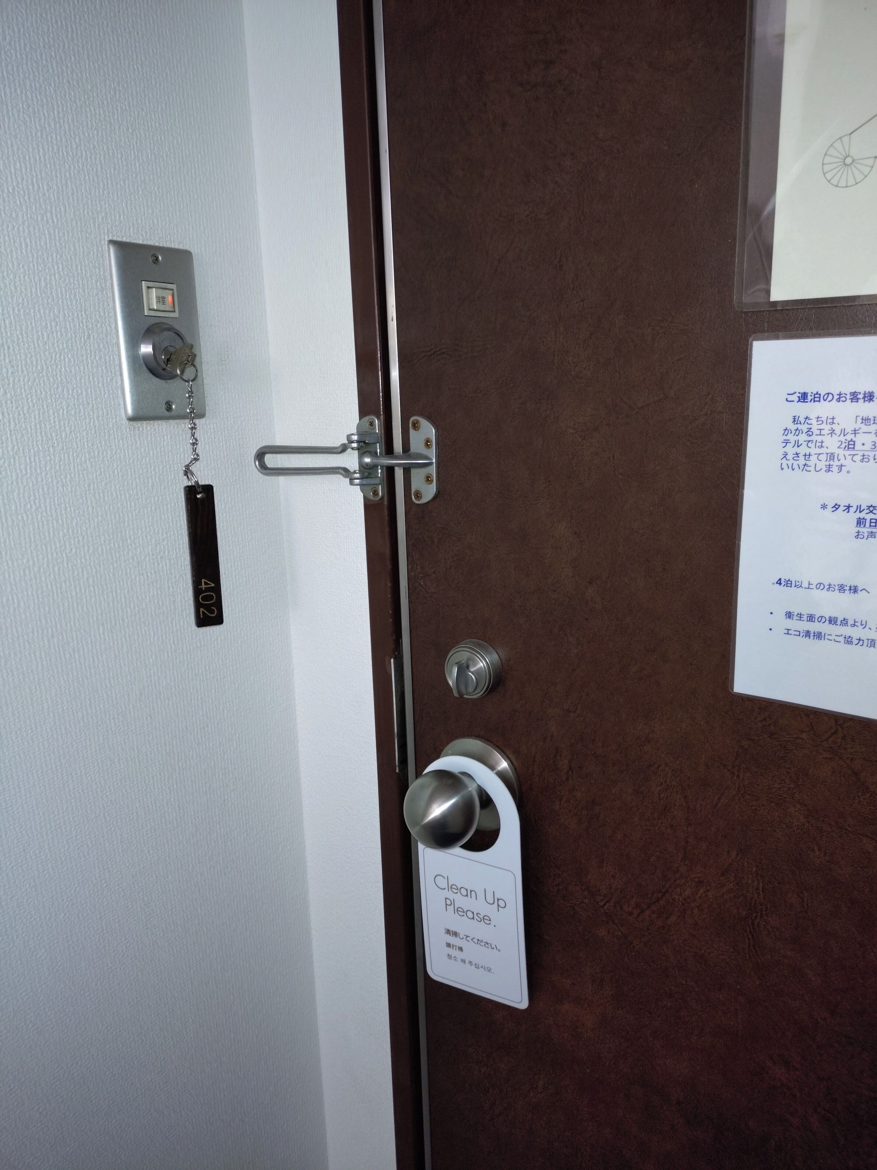 Una puerta con cerradura y un llavero, además de un cartel que dice 'Por favor, limpiar'.