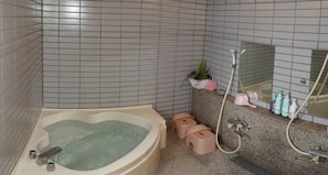 A bathroom with a bathtub, a shower, and a vanity with toiletries. - Pension Snowfall Meteor (Kaminoyama)