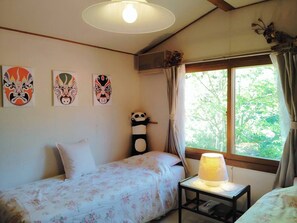 A room with a bed, a bedside table with a lamp, and three wall-mounted paintings. - Pension Snowfall Meteor (Kaminoyama)