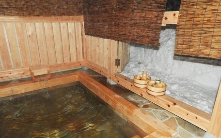 A wooden sauna with a stone floor, wooden benches, and a stone wall.