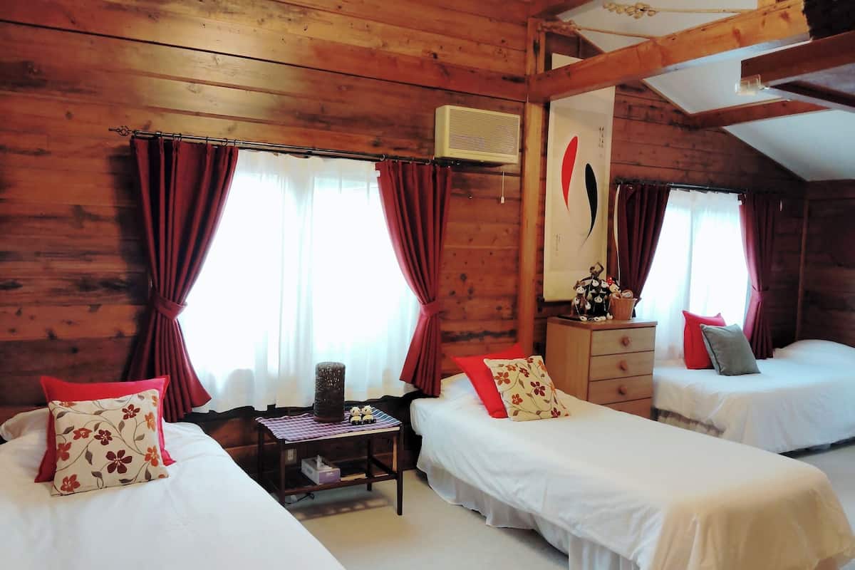A cozy cabin-style room with two single beds, a small table, and a dresser.